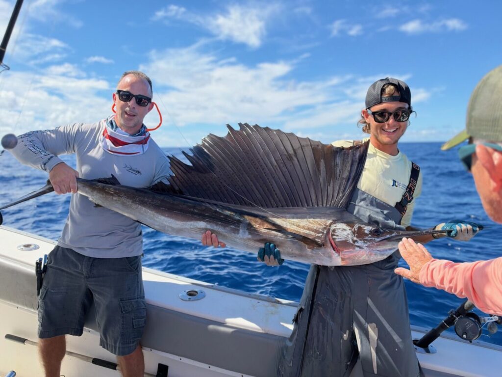 Guests displaying a sailfish aboard the fishing boat