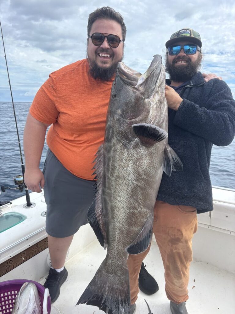 Two smiling anglers displaying a large catch aboard the boat