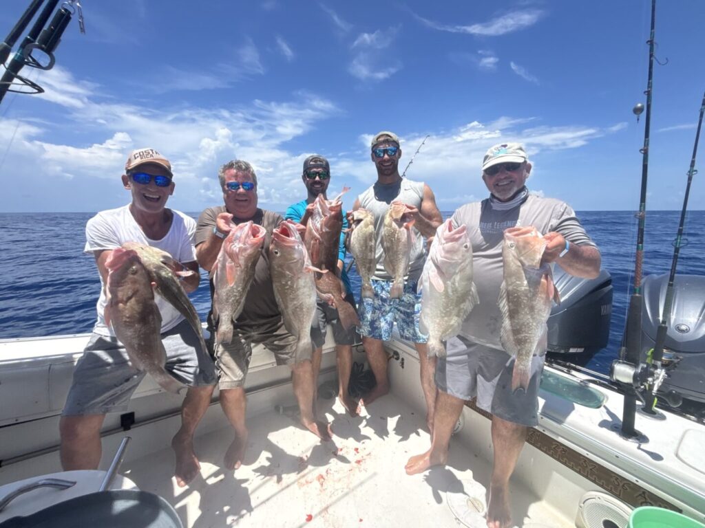 A group of anglers holding their catches aboard Salty Dog Charters