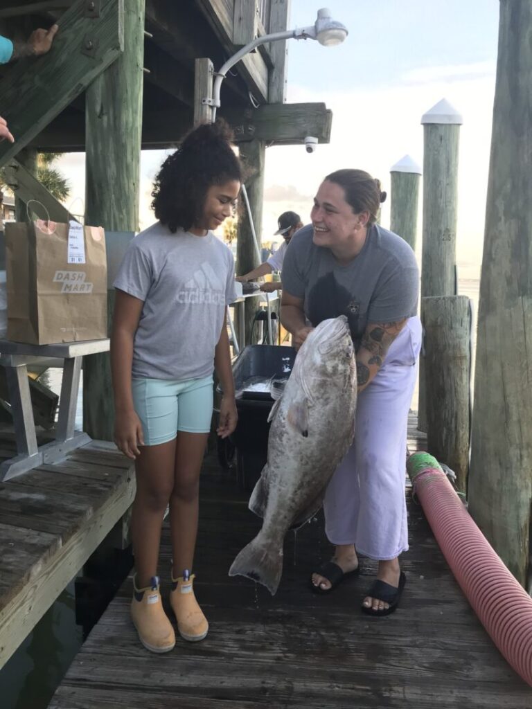 Guests displaying a catch together beside the dock