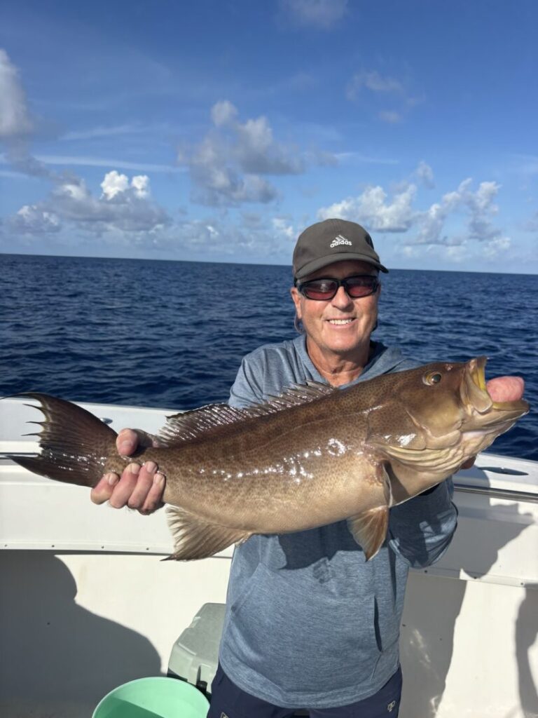 An angler holding a catch with the sea behind