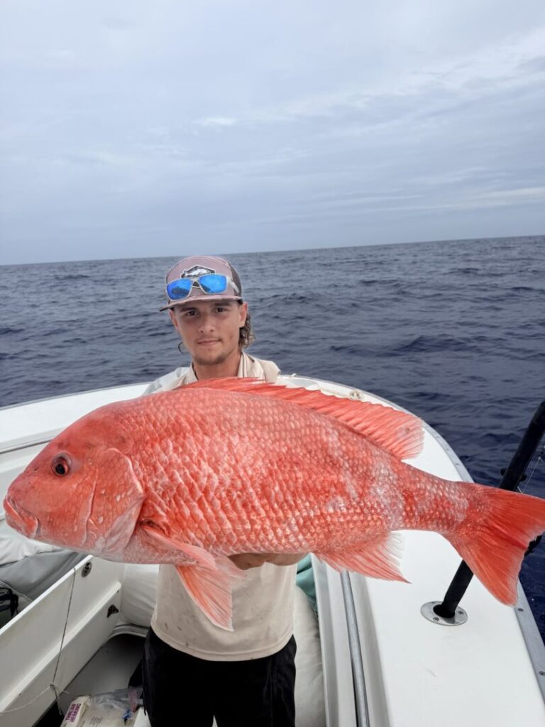 An angler showing an offshore catch with the ocean behind